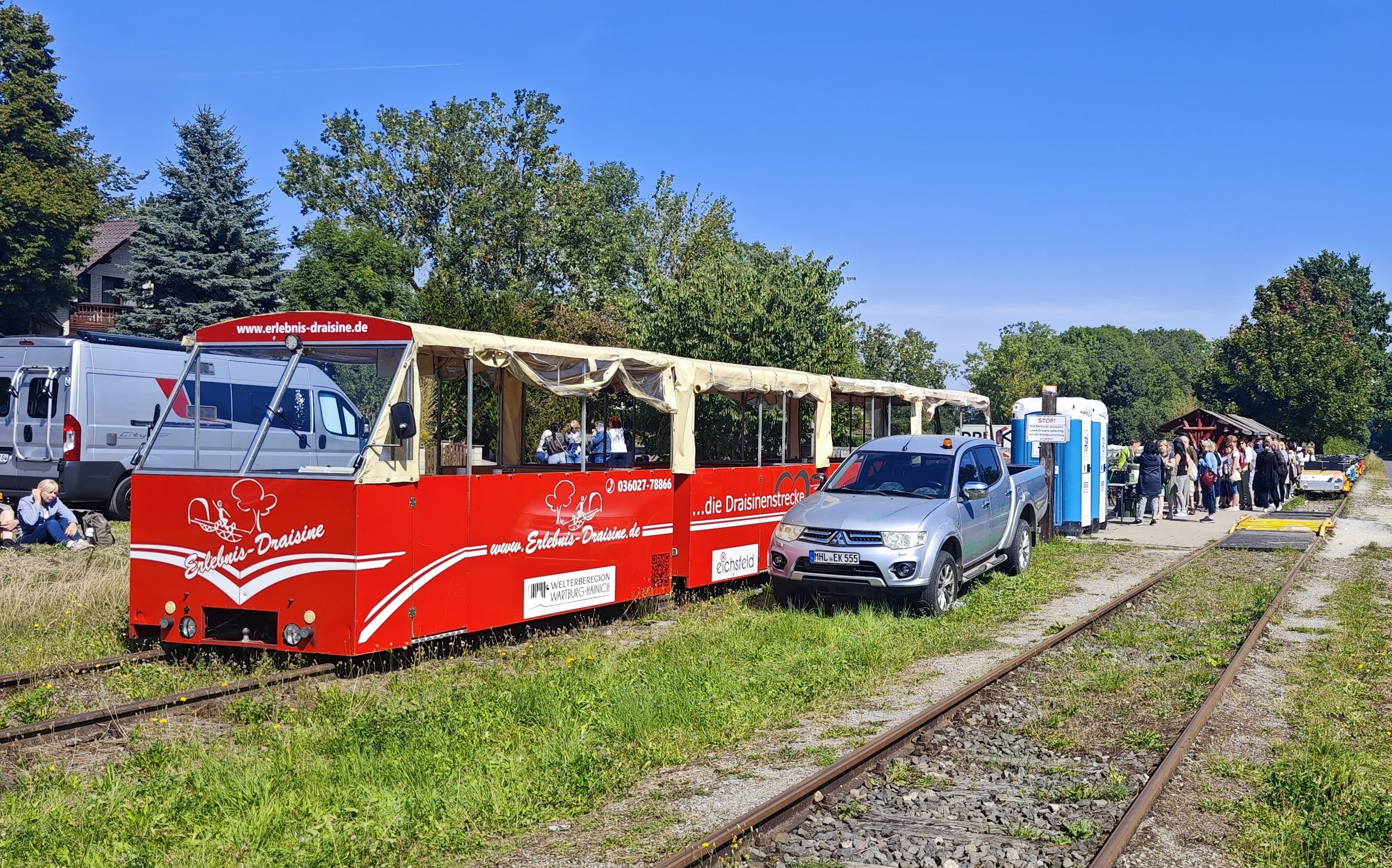 Elektrischer Kanonenbahn-Zug mit Gruppe an einer Haltestelle